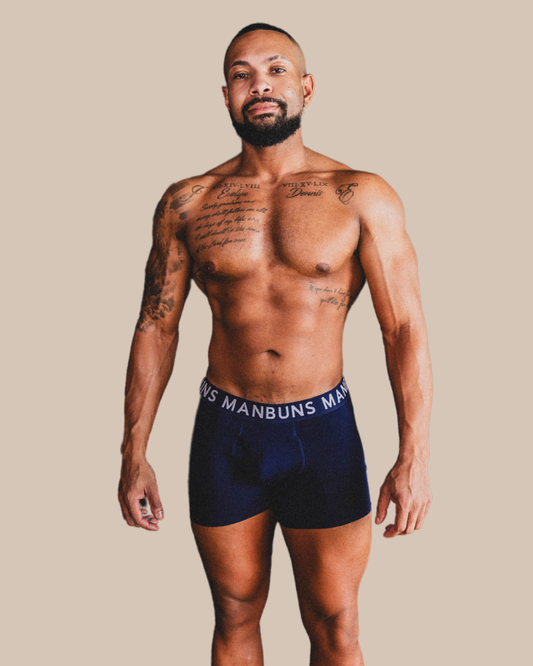 Man wearing navy blue underwear with visible branding against a beige background