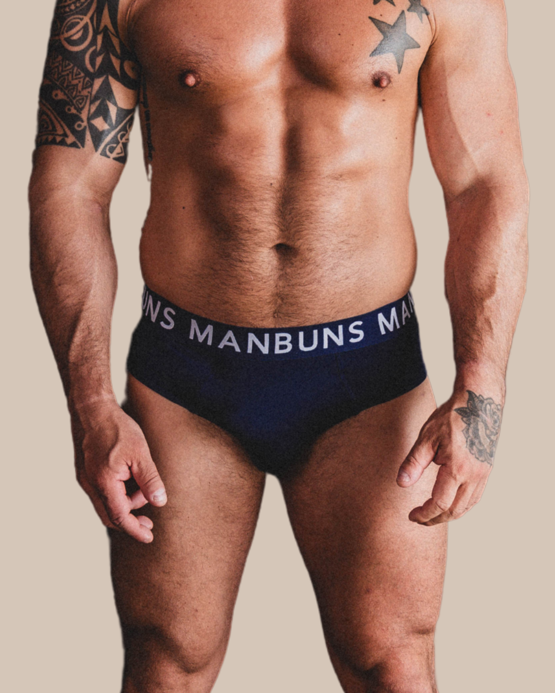 Man wearing black underwear with 'MANBUNS' branding on a beige background